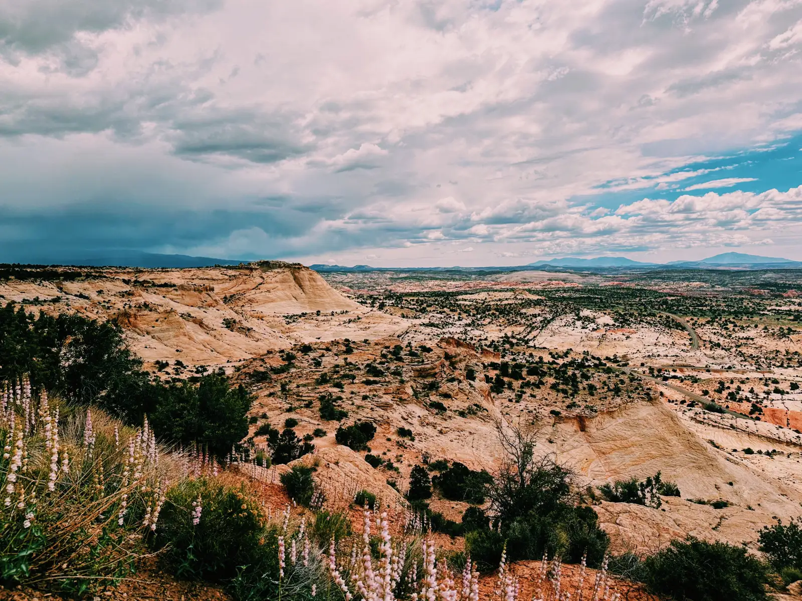 View of the San Rafael Swell in central Utah with many colors of rocks as a thunderstorm moves off in the distance
